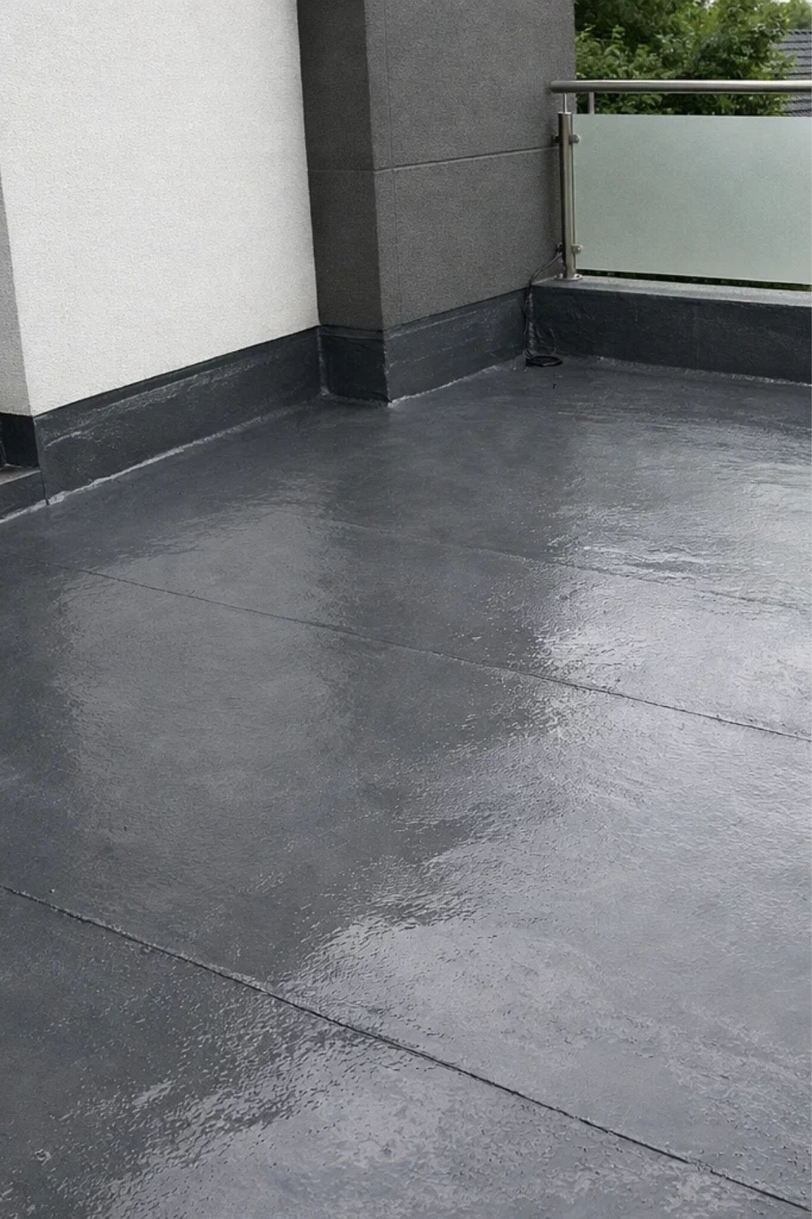 Application manuelle d’un revêtement sombre et uniforme sur une surface extérieure en béton, dans un contexte résidentiel pour bâtiments à Saint-Zotique
